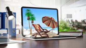 Umbrella, sunbed and plam trees on sand standing on notebook computer. Online travel destinations booking concept