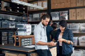 Shot of two colleagues using a cellphone in a workshop